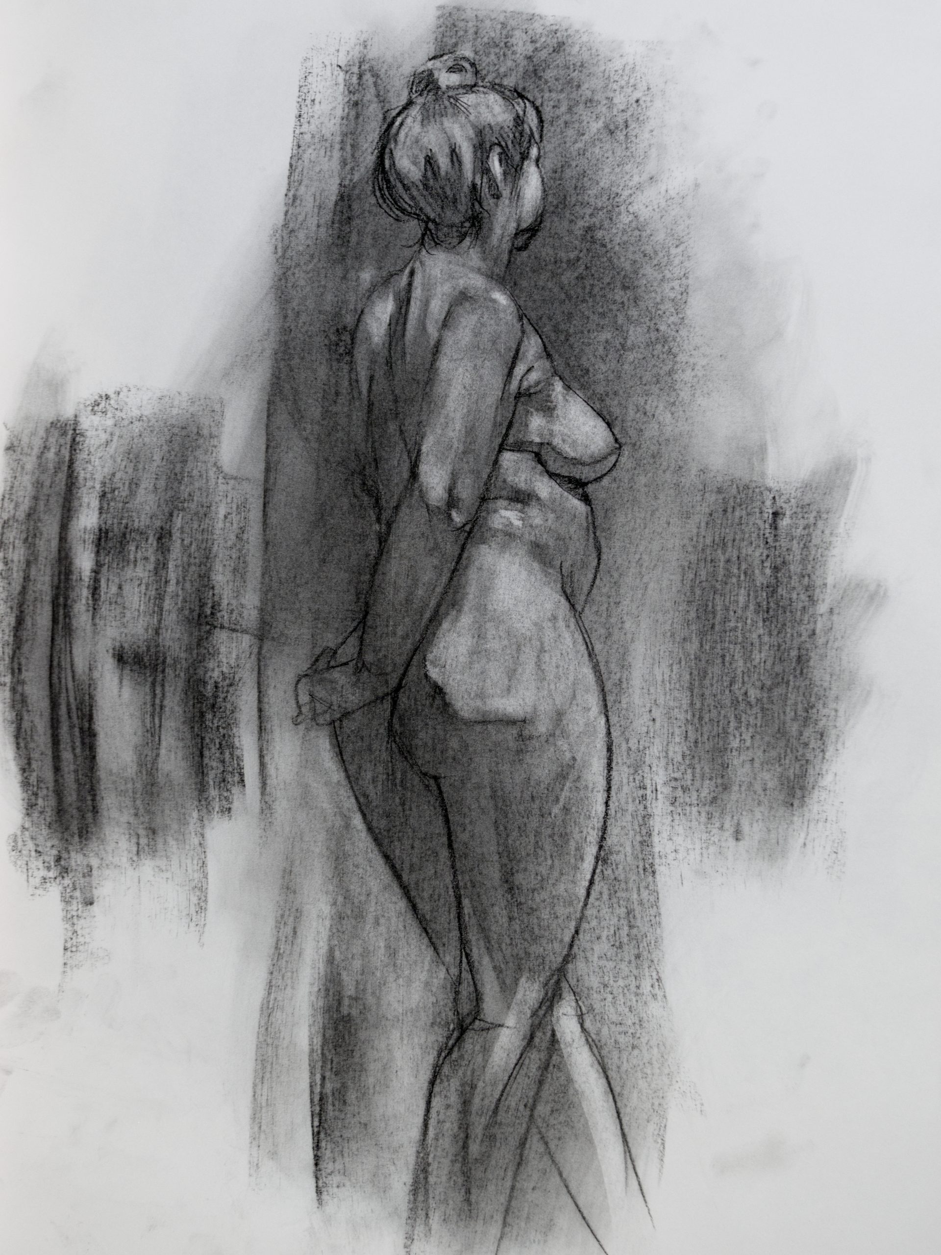A charcoal drawing of a nude, standing woman from behind.